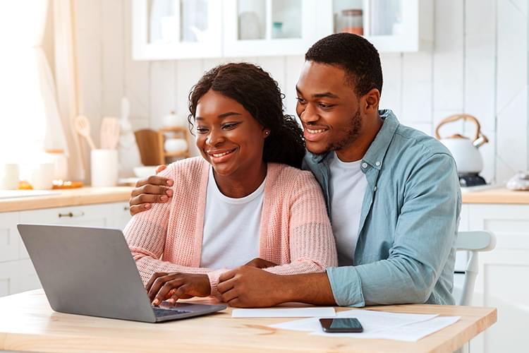 Smiling woman taking notes in front of laptop